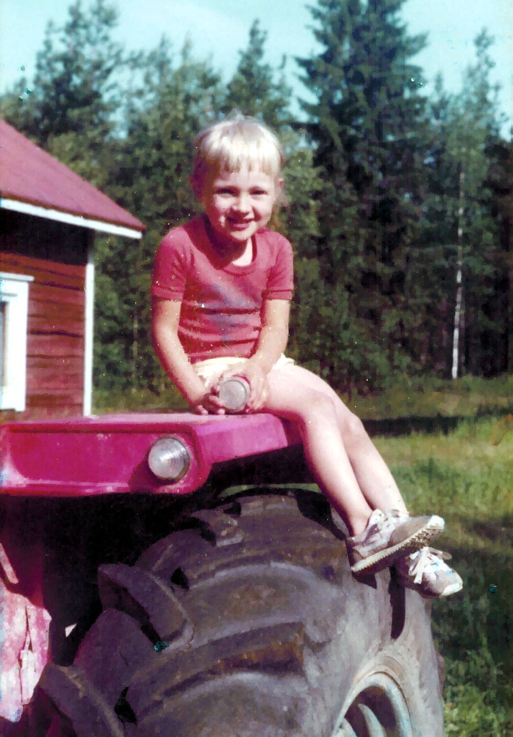 Pieni tyttö istuu traktorin renkaalla.